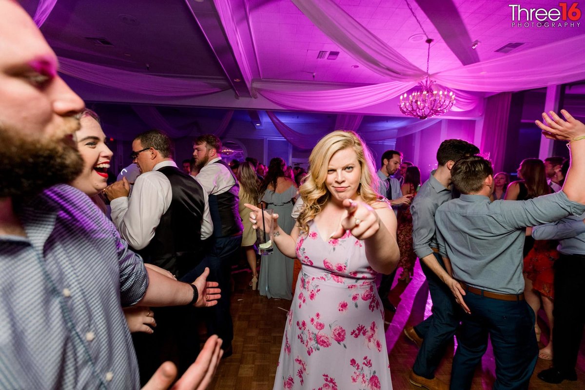 Girl dancing at wedding reception with drink in hand