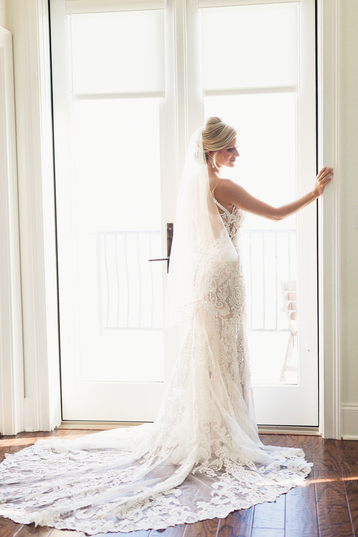 Bride Pictured from Behind Standing in Sunny Glass Doorway Before her Destination Wedding in Destin Florida