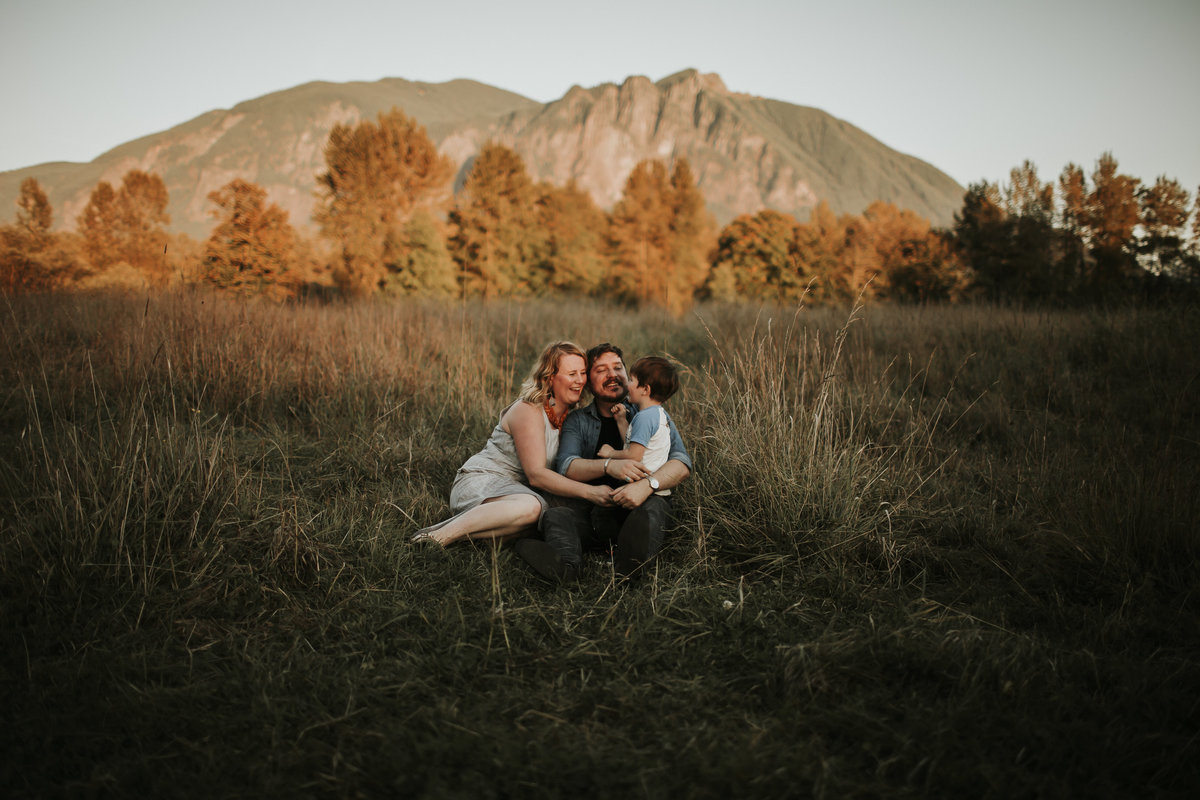 Seattle wedding photographer, Marnie Cornell, laughs and smiles with her family in a field