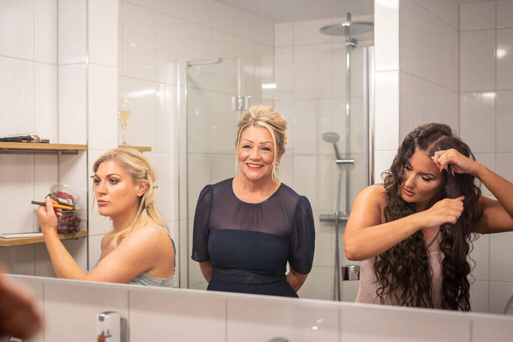 Bridesmaids putting on makeup in hotel mirror