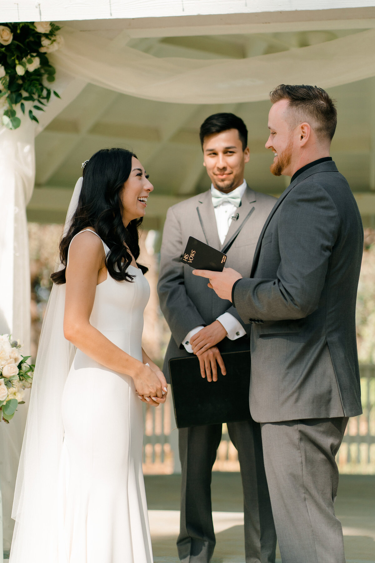 bride ad groom laughing at each other while officiant is smiling at the groom