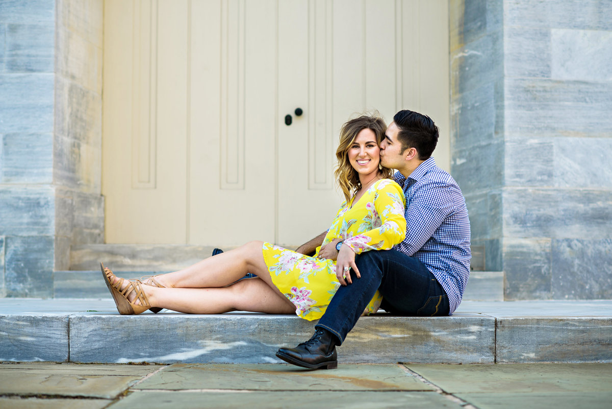 A pregnant couple sit in front of a building in old city.