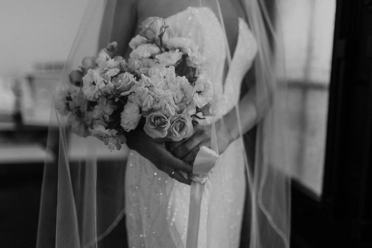 Elegant black and white image showcasing the bride gracefully holding a stunning wedding bouquet