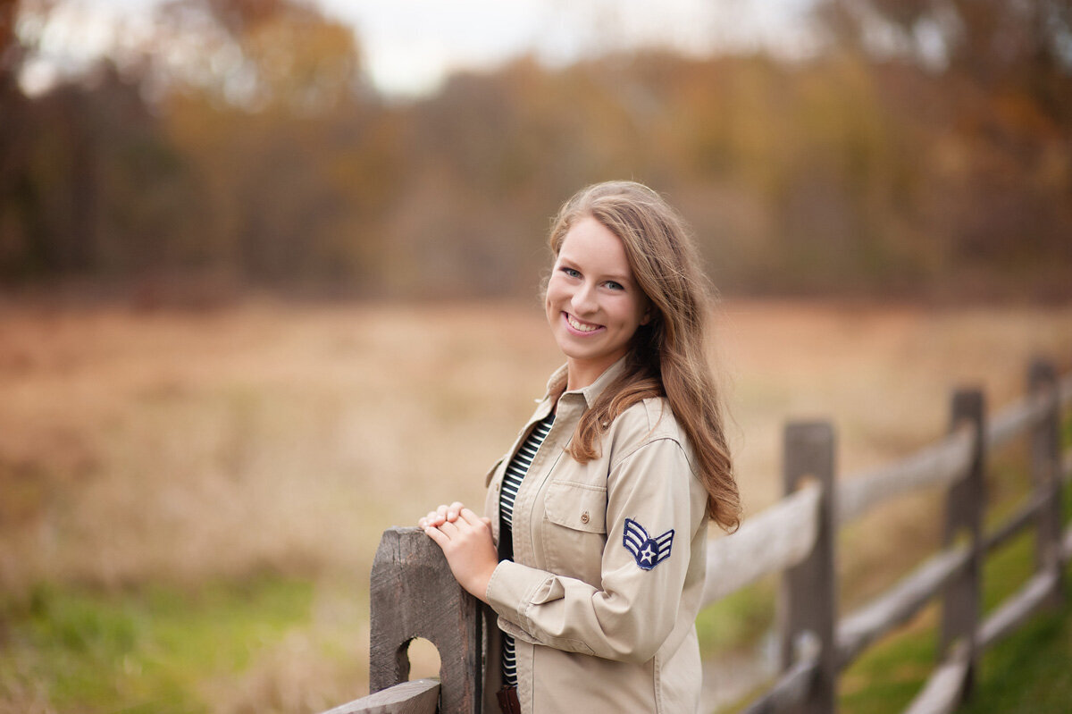 Senior session of young woman standing near fence