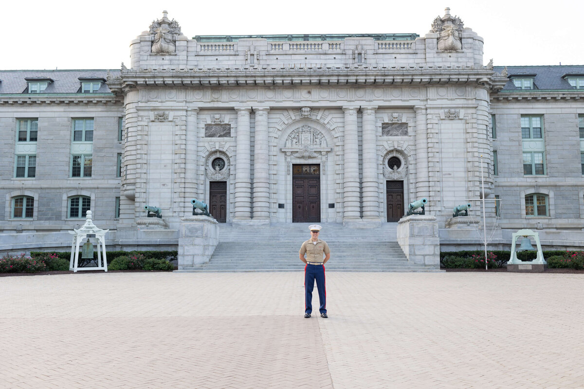 Naval Academy graduate at parade rest in front of Bancroft Hall.