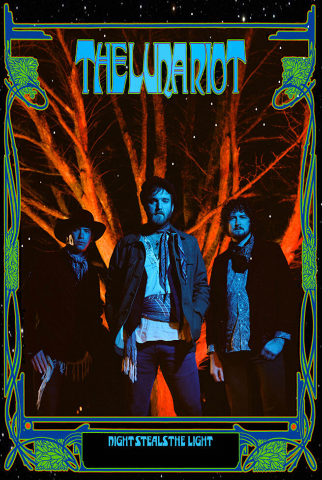 Poster for Album Release Title Night Steals The Light Band The Luna Riot three members standing in front of leafless tree lit up in red