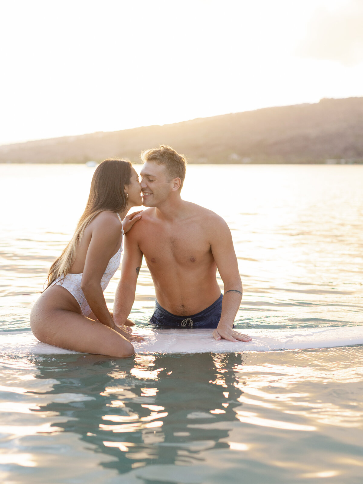 couple-on-surfboard-kissing-at-sunset-in-ocean