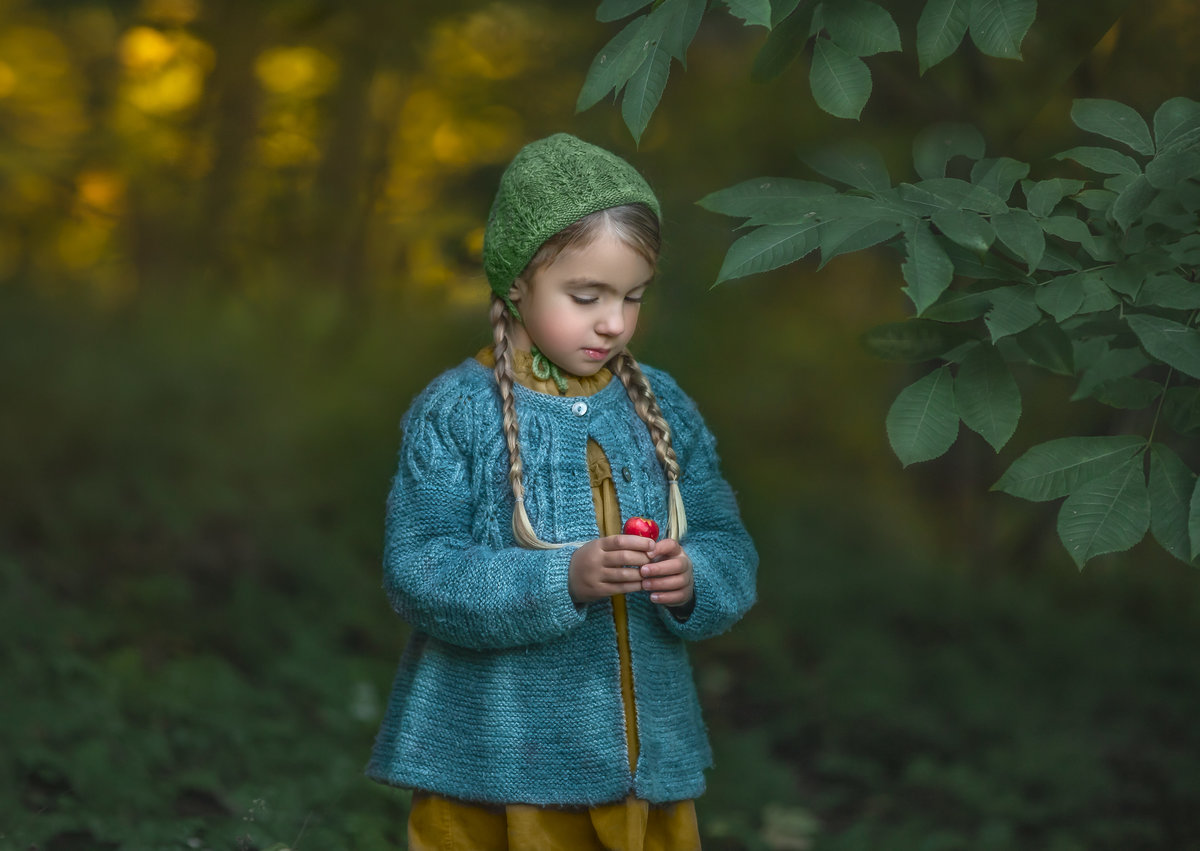Young girl dressed in vintage knits standing in a vibrant forest located in Ottawa.