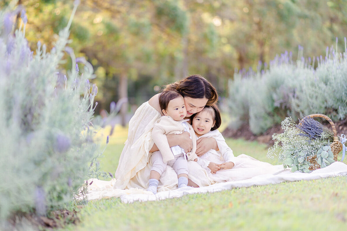 Mum snuggling with kids in a flower field captured by brisbane family photographer Hikari Lifestyle Photography.