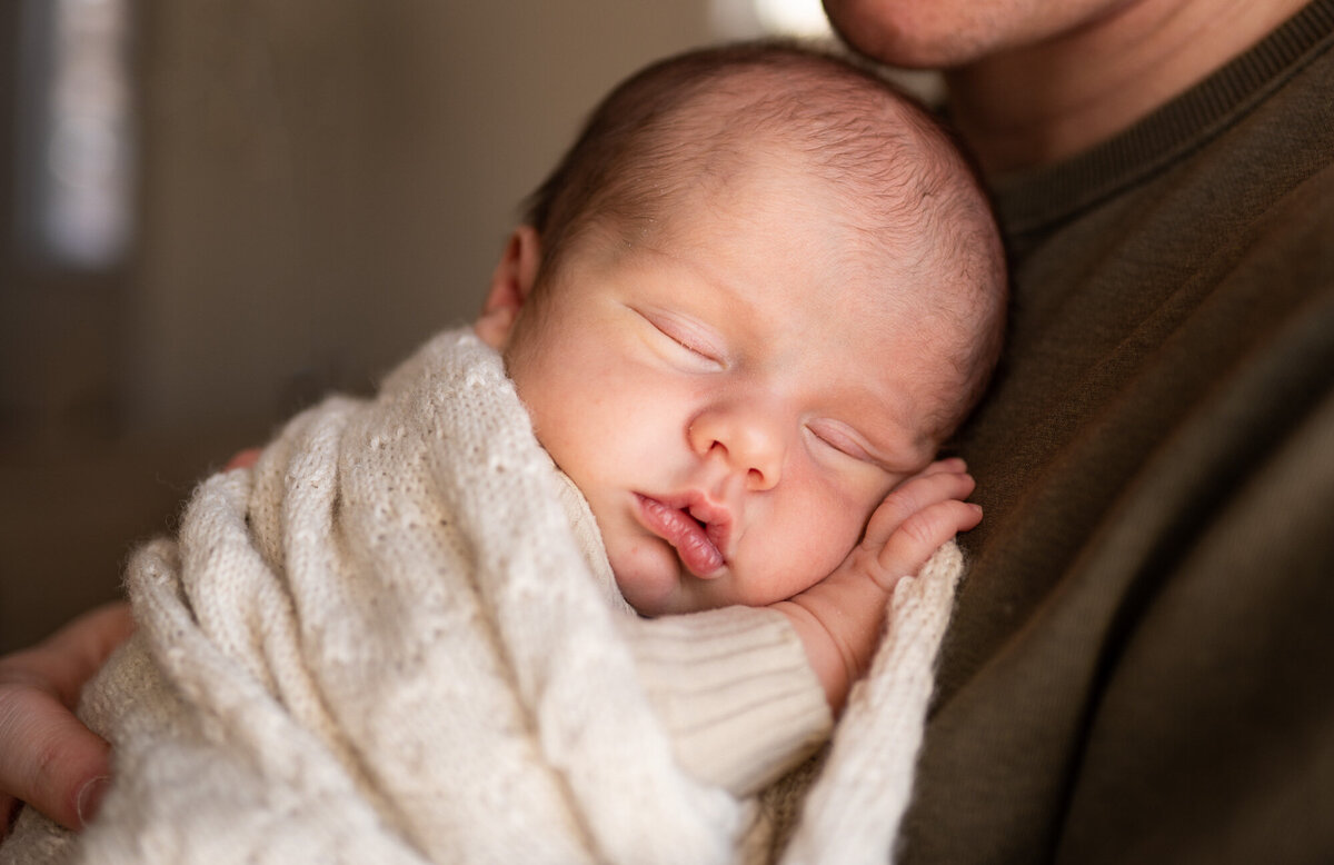 newborn baby boy wrapped in a beige blanket, sleeping