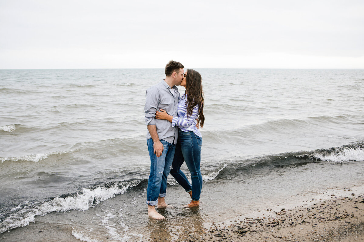 Engaged couple kissing with feet in the ocean