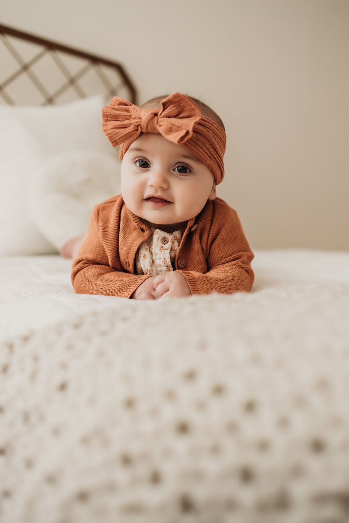 four month old milestone session of baby girl in rust color outfit and bow at home