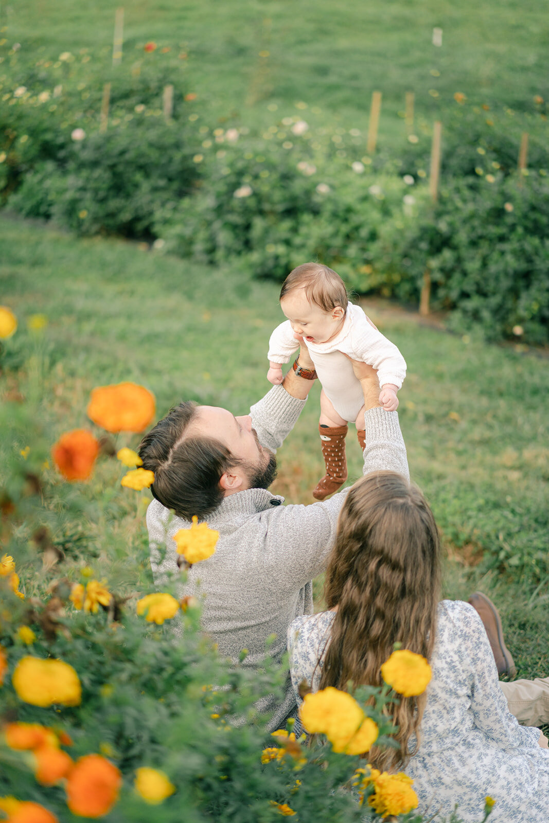 mom and dad holing baby in asheville flower garden