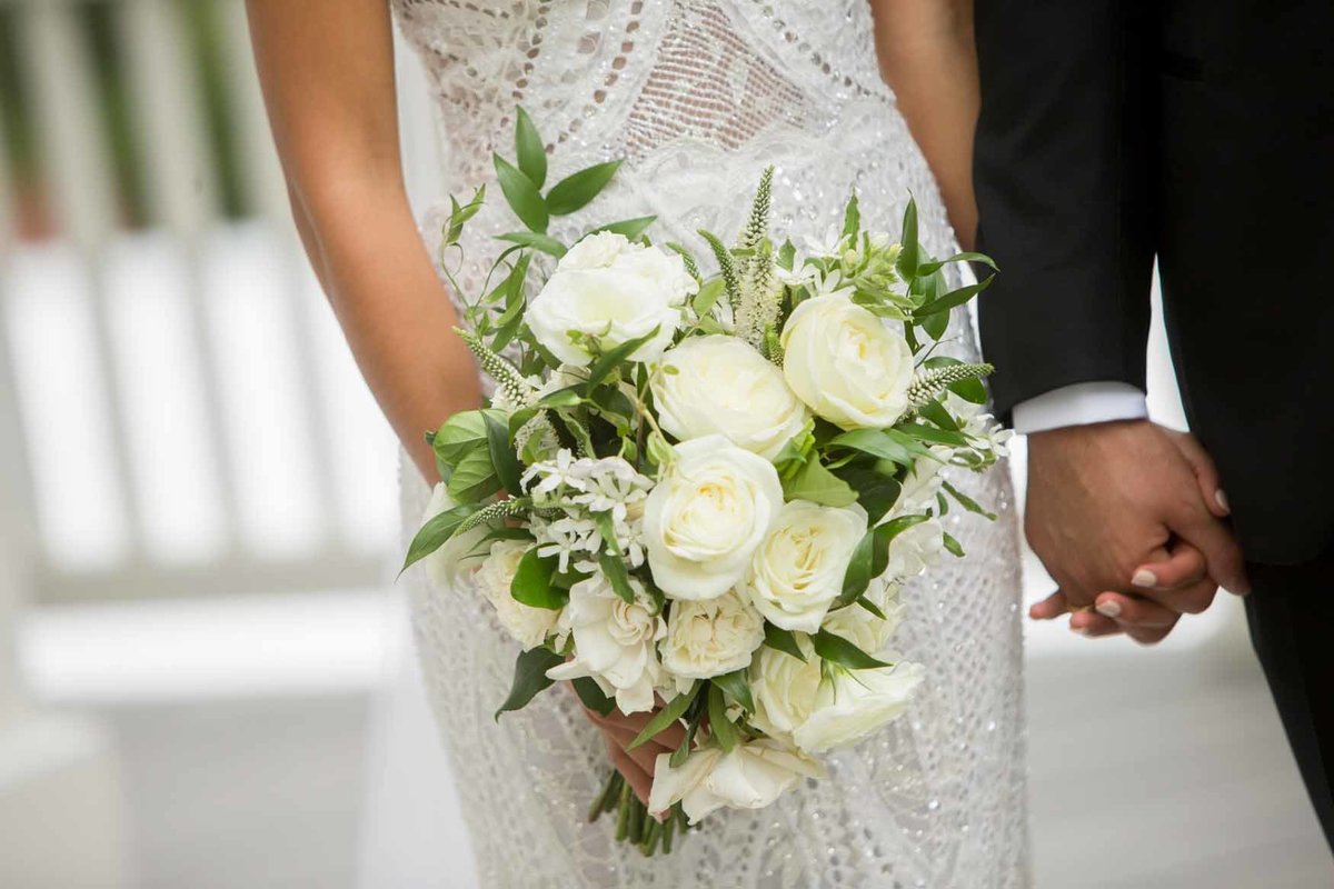 Bride holding white rose bouquet with greenery