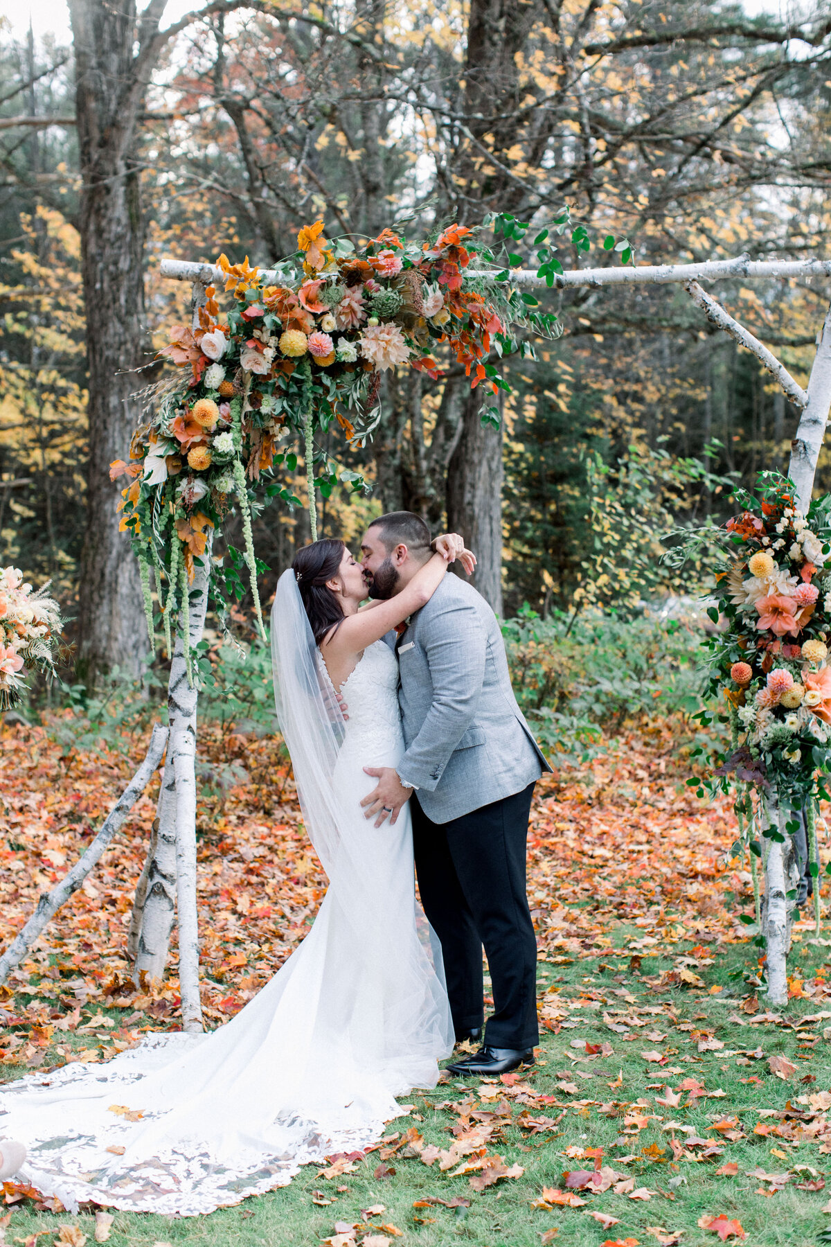 bride and groom kissing under the wedding ceremony arch at fall wedding in Franconia New Hampshire
