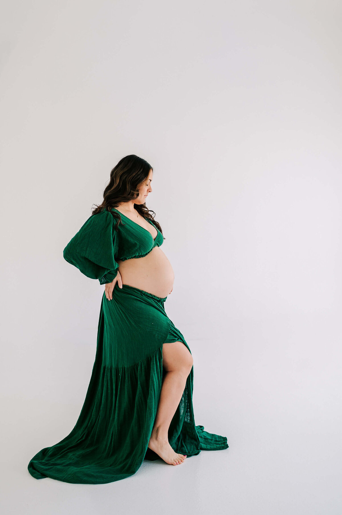 pregnant mom in green dress holding baby bump captures by Springfield MO maternity photographer Jessica Kennedy of The XO Photography