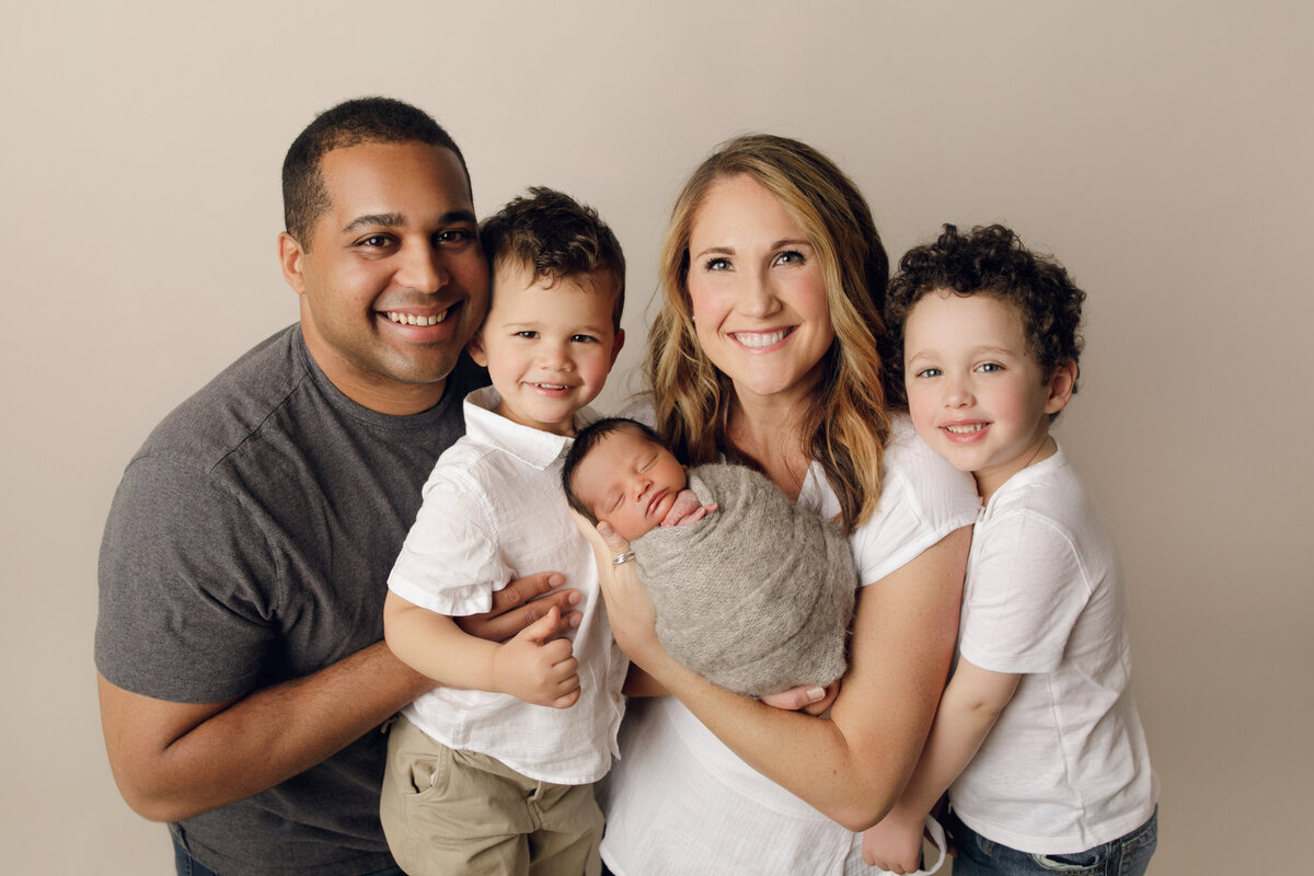 family of 5 in neutral clothing hugging