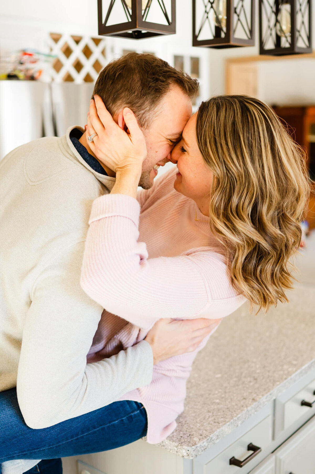 Playful husband and wife embracing on a countertop during couples session near Naperville, IL.