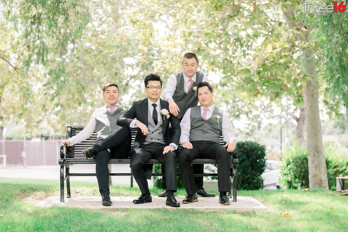 Groom poses with his Groomsmen on a park bench