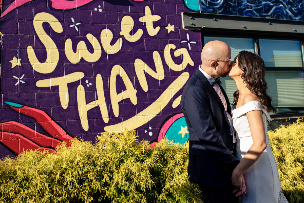 Bride-and-groom-kissing-in-front-of-the-Sweet-Thang-graffiti-art-wall-near-Eventide-Brewing-in-Atlanta