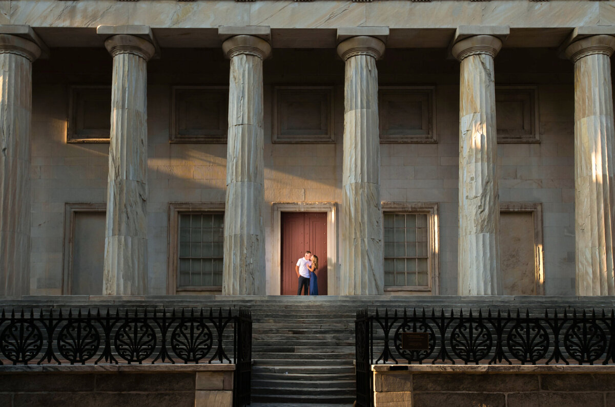 Man and woman post in front of second bank of United States for their engagement session