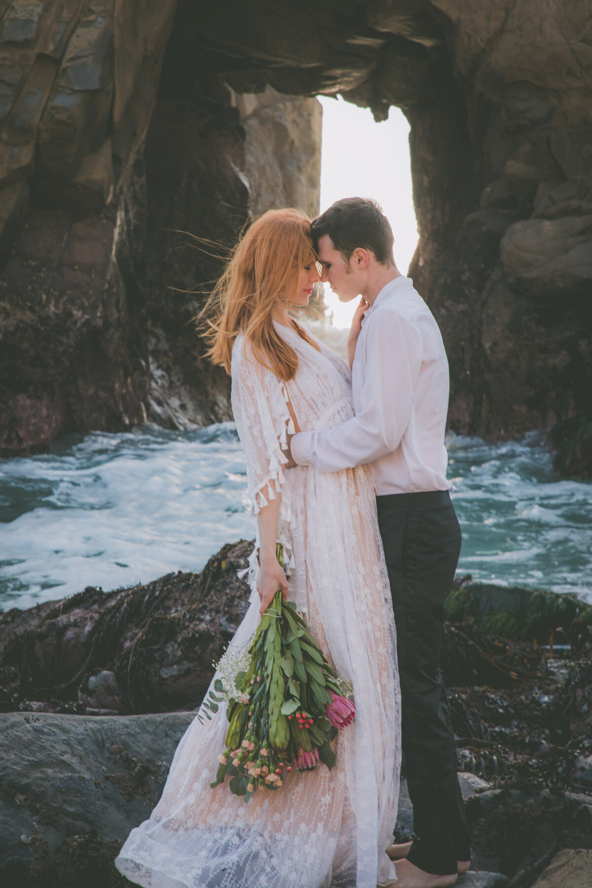 Bride & groom touch foreheads with Pfeiffer beach keyhole view.