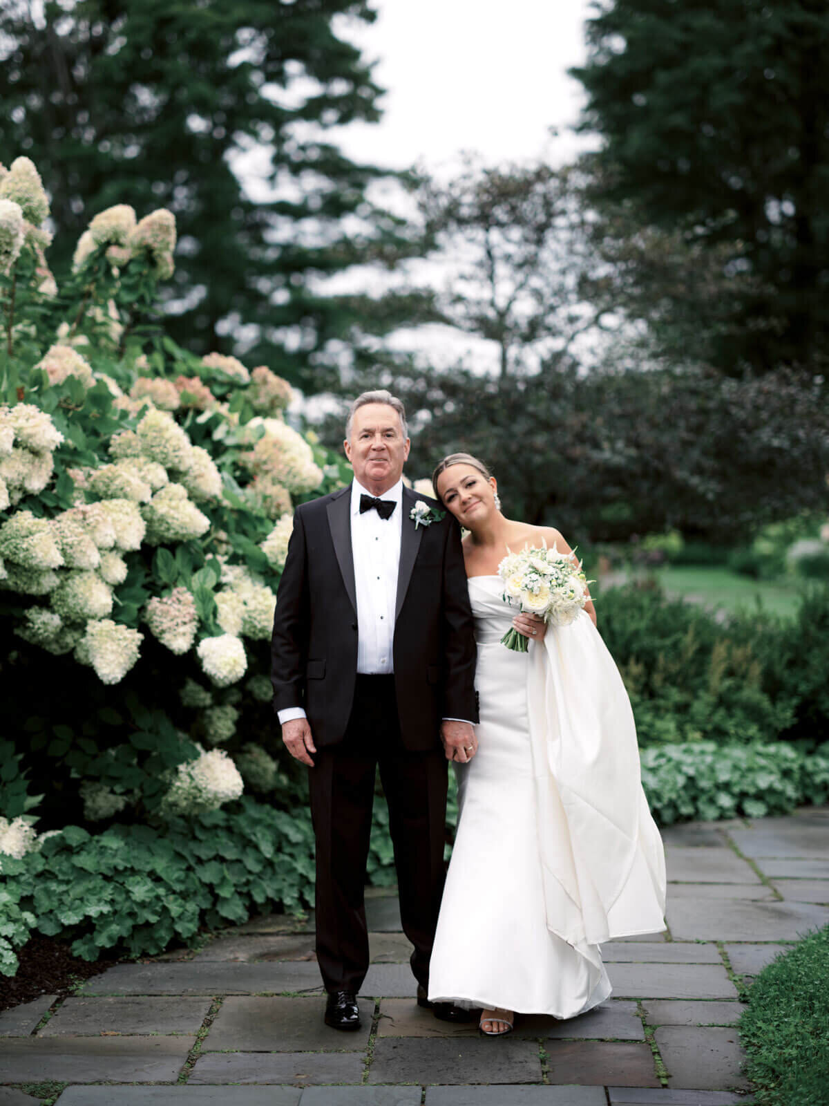 The happy bride and her father are standing on a walking path in a beautiful garden at The Lion Rock Farm, Sharon, CT. Image by Jenny Fu Studio