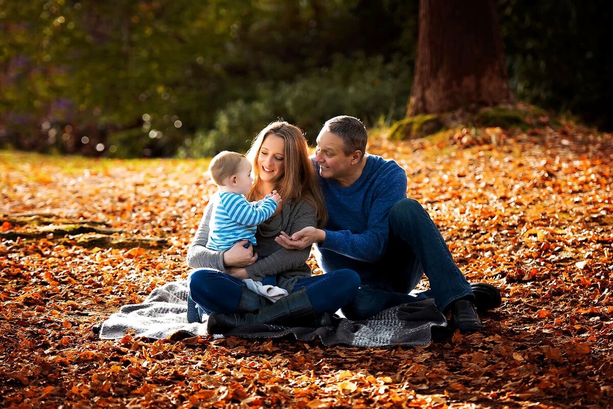 Fall family mini session in Vancouver with mother, father and infant son sitting on a blanket