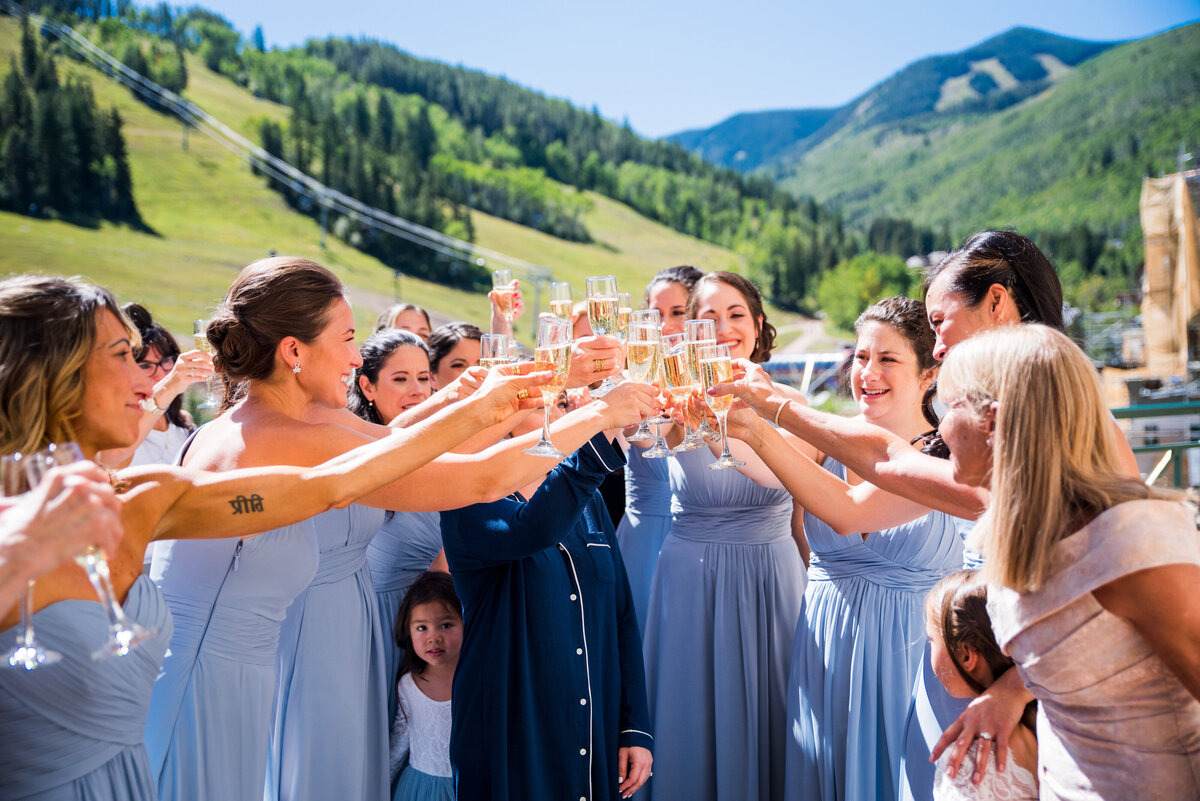 A bride and group of bridesmaids "cheers" some champagne.