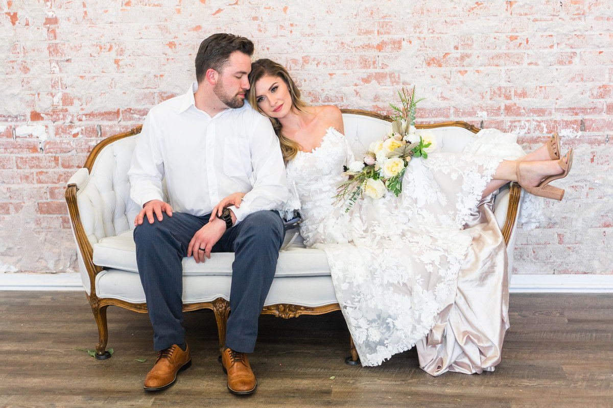 Bride and Groom cuddling on white love seat