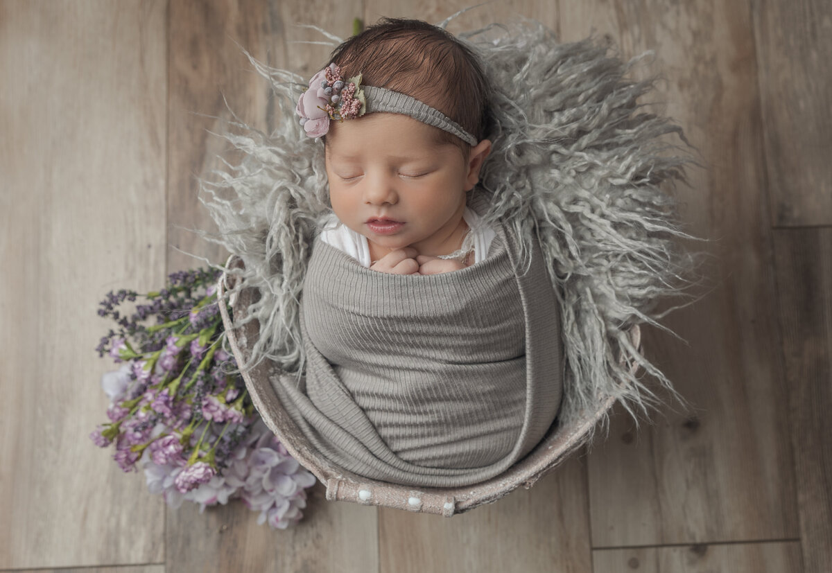 newborn baby girl in a bucket with flowers
