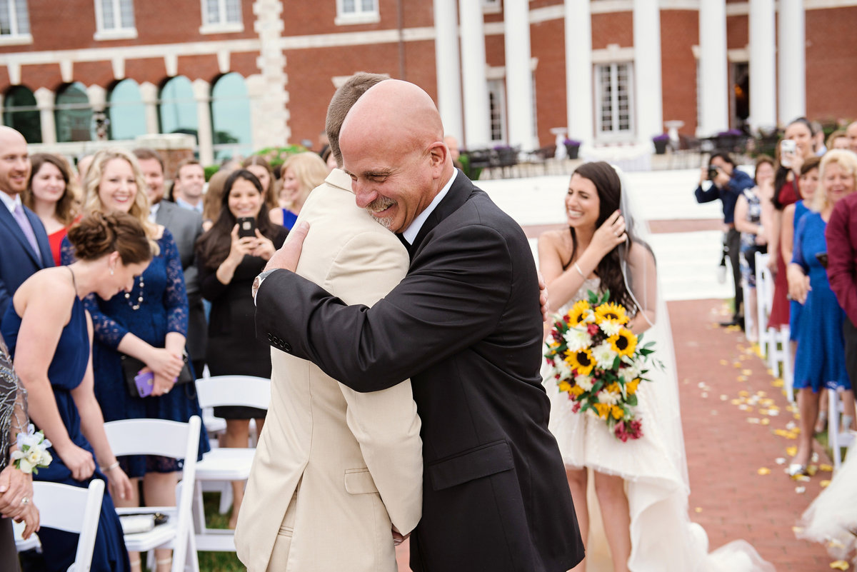 Father of the bride hugging the groom during a wedding ceremony at The Bourne Mansion