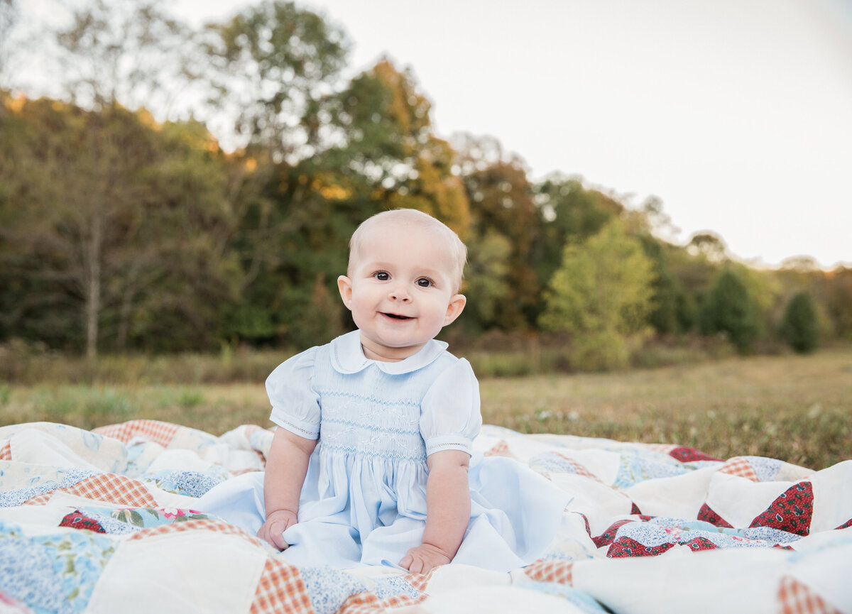 little girl sitting on a blanket  for family photo session
