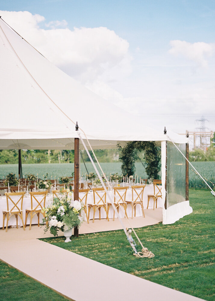 white canvas wedding marquee with complete table setting styled with natural cross chairs