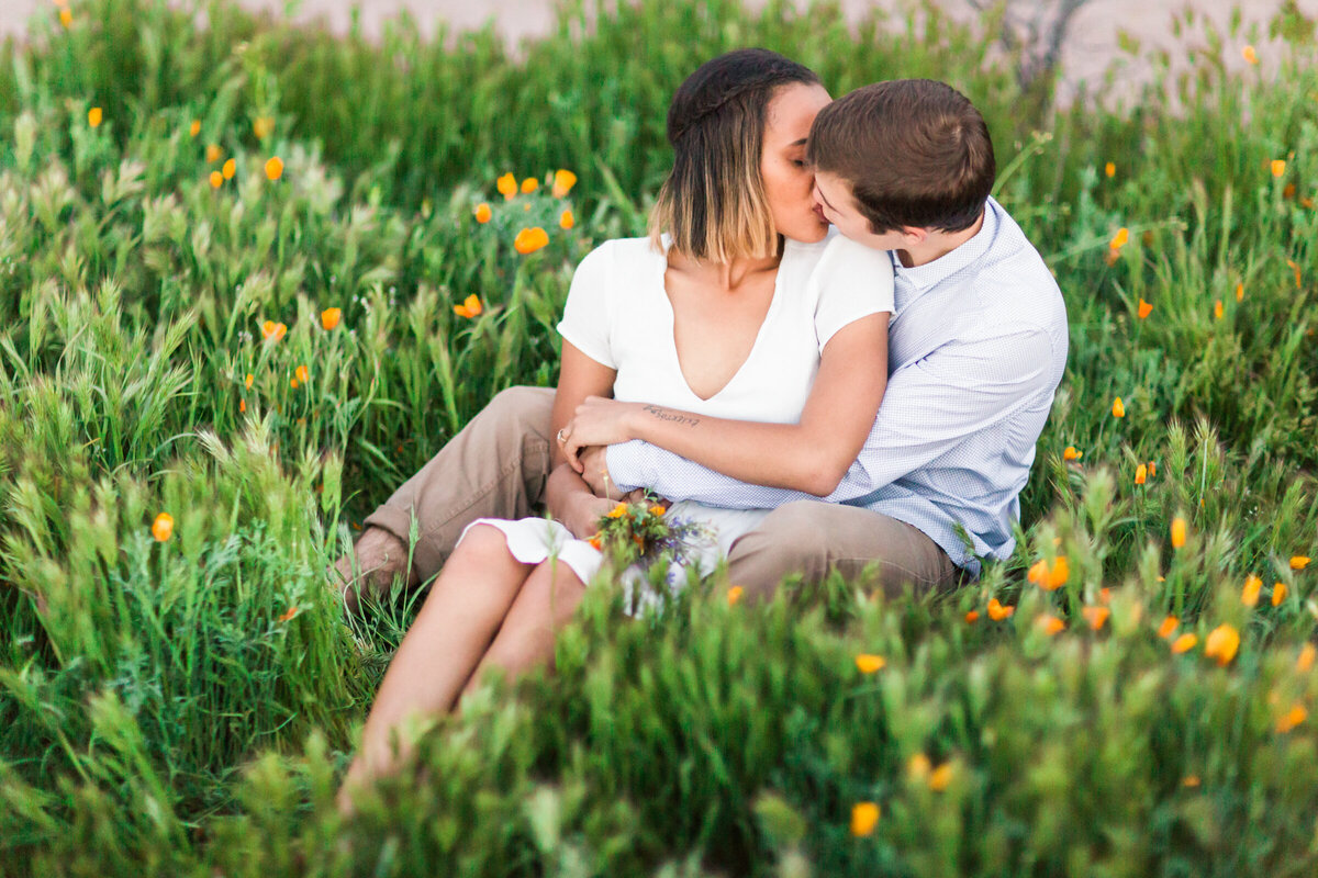 couple snuggling together in the grass and kissing