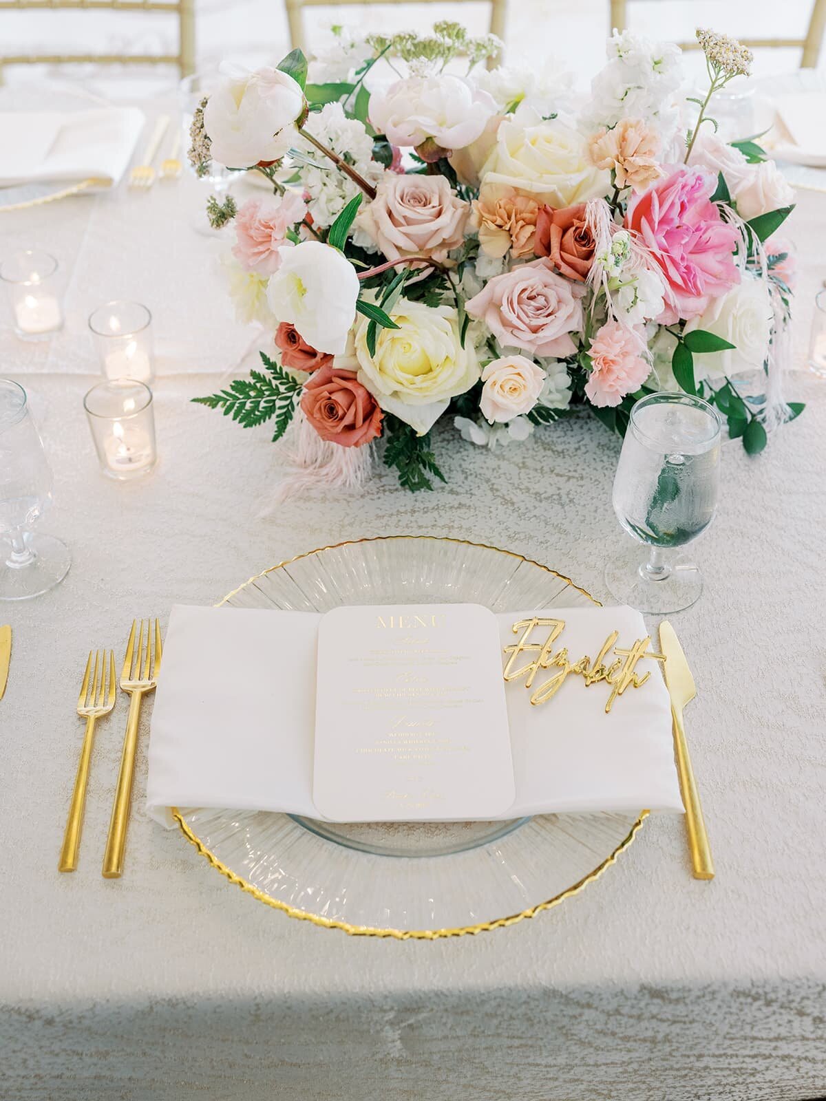 elegant table setting with bright pink bouquet and gold trim plates and silverware