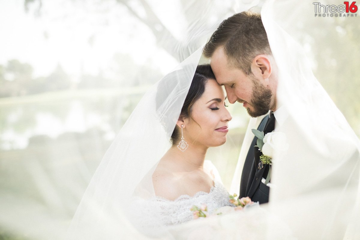 Bride and Groom share a tender moment under her veil