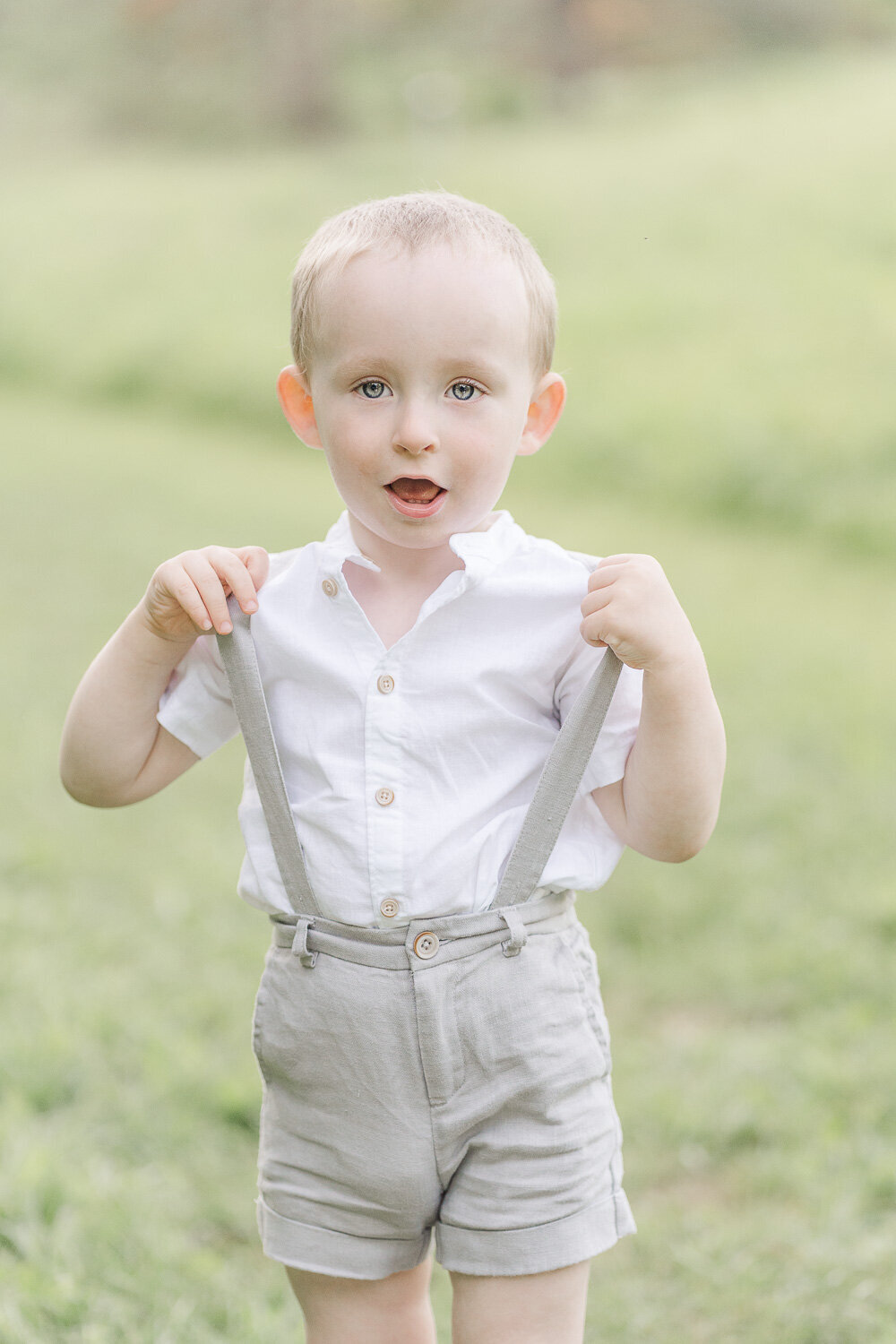 toddler playing with his suspender during spring minis taken by a Centreville, Virginia photographer