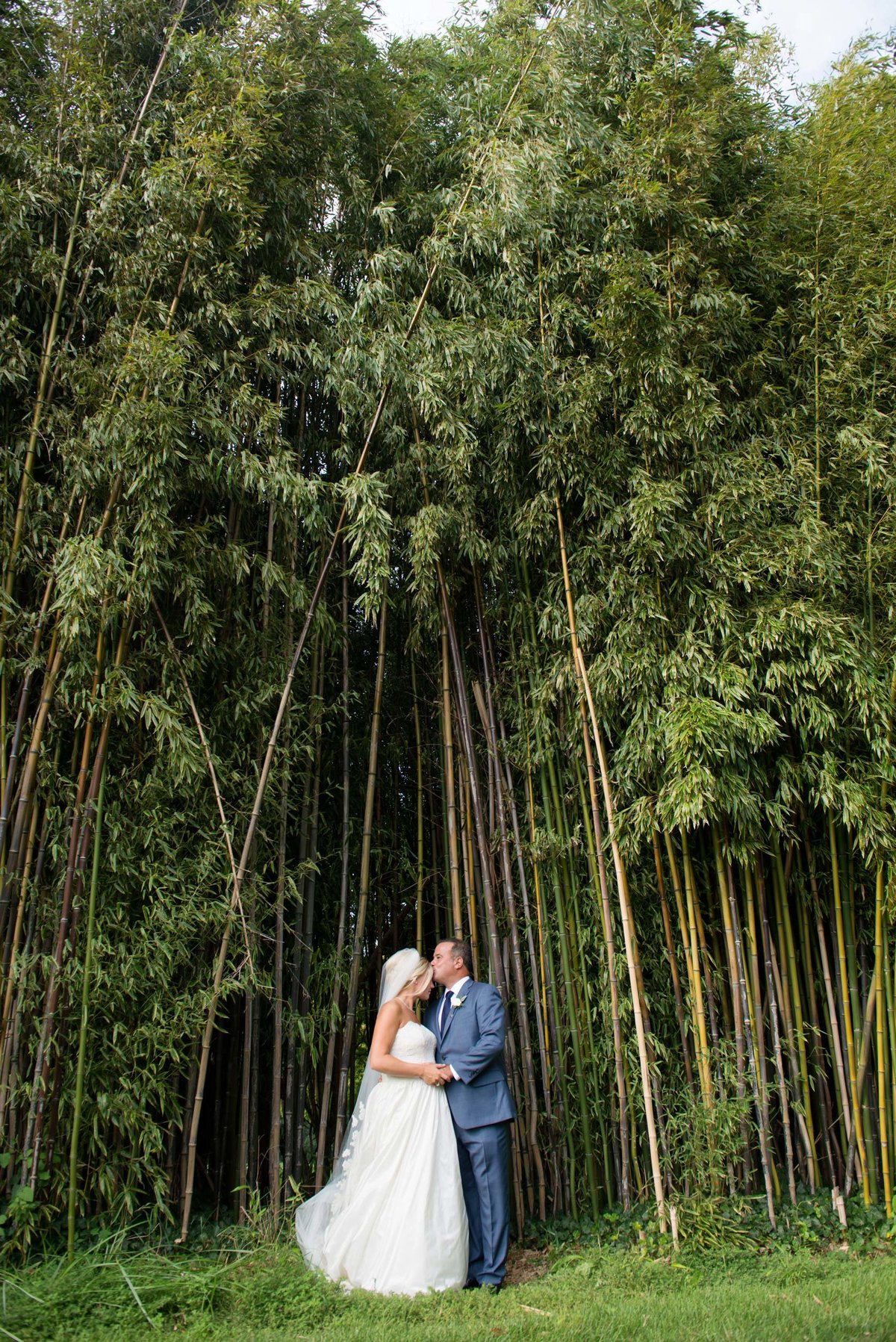 Bride and groom kissing in from of trees at Huntington Crescent Club