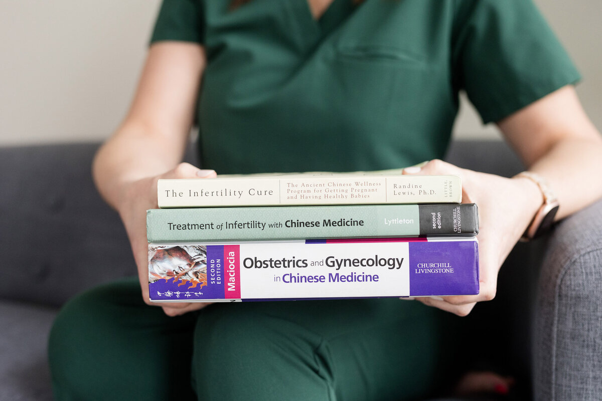 Jamie holding a stack of Women's Health and Fertility themed books
