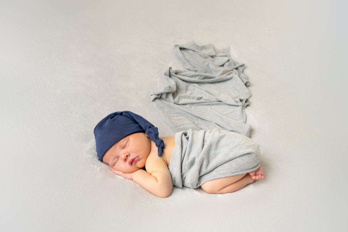 newborn-baby-wrapped-in-grey-with-blue-hat
