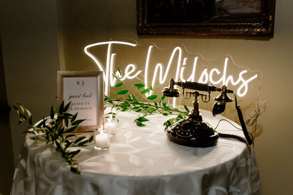 Neon sign, greenery and antiques decorate the guest book table at Chicago wedding.