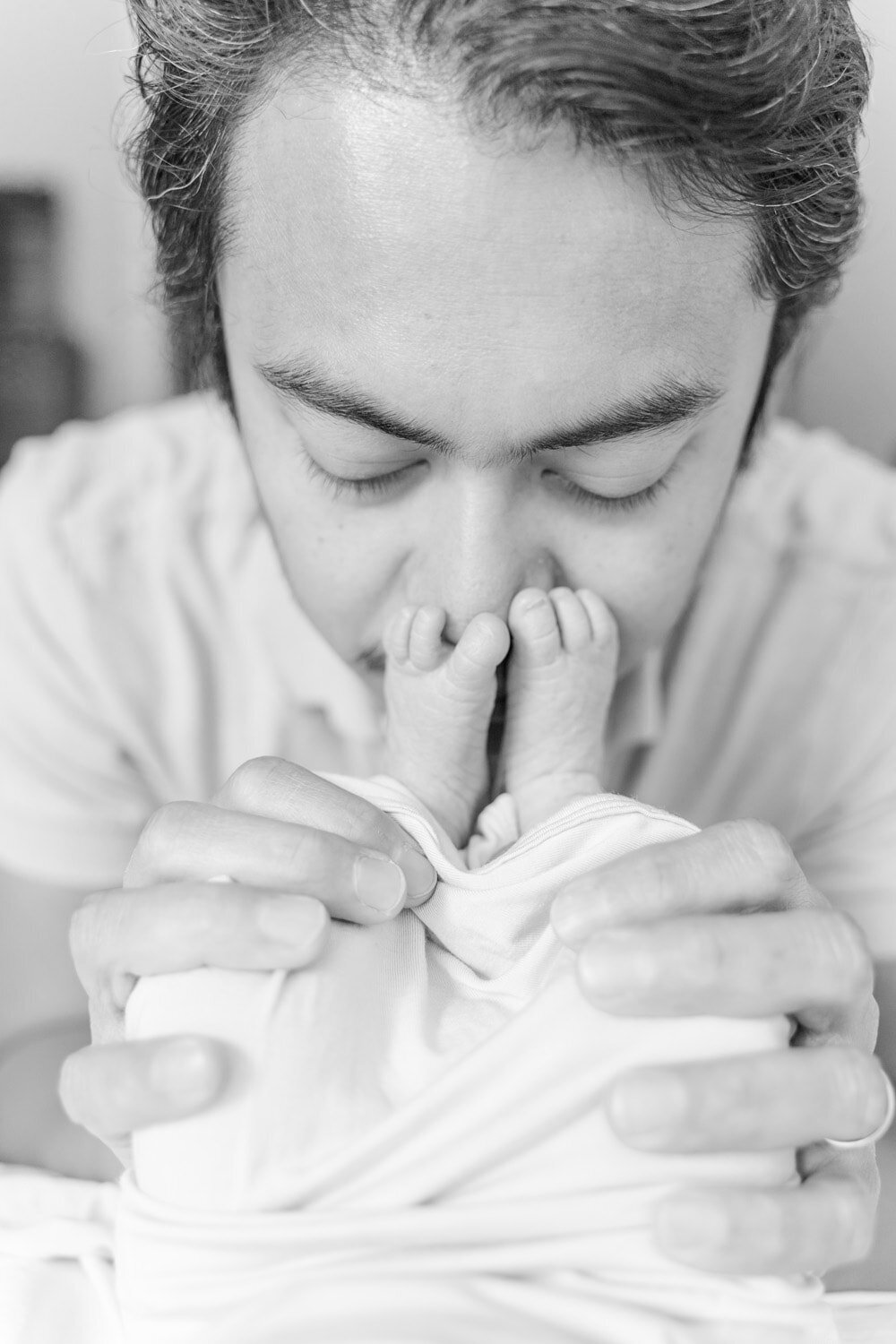 dad smelling baby's feet during lifestyle newborn photos in Northern VA