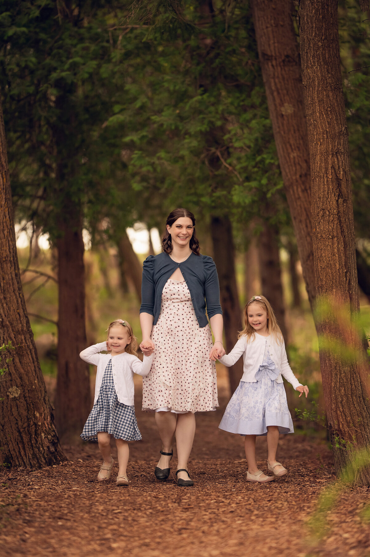 A mom and her two daughters stand amongst tall trees at Retzer Nature Center in Waukesha.