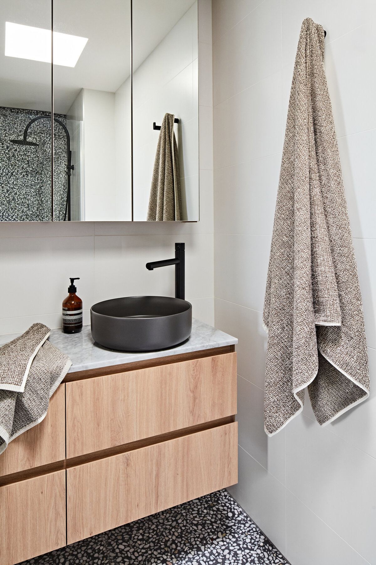 Contemporary bathroom with terrazzo tiles, black fixtures, and floating timber vanity