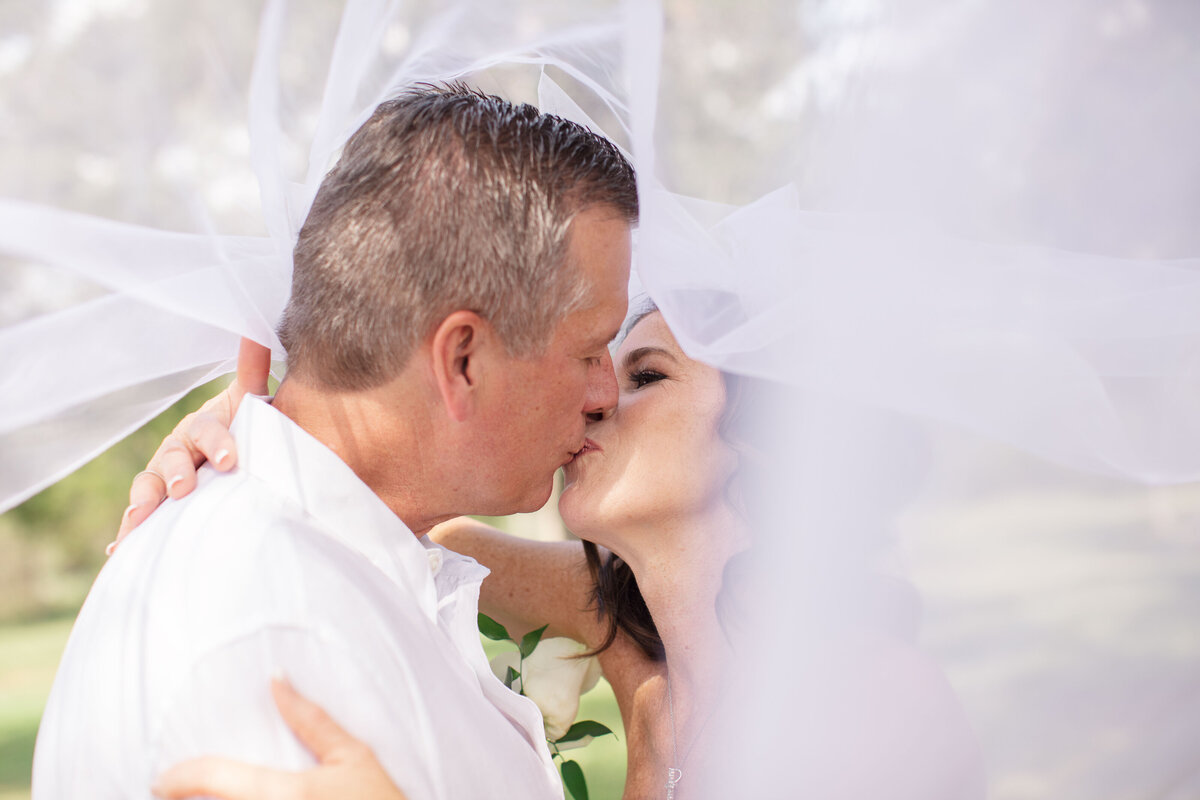 bride and groom kiss with veil over heads at wedding near Austin Texas