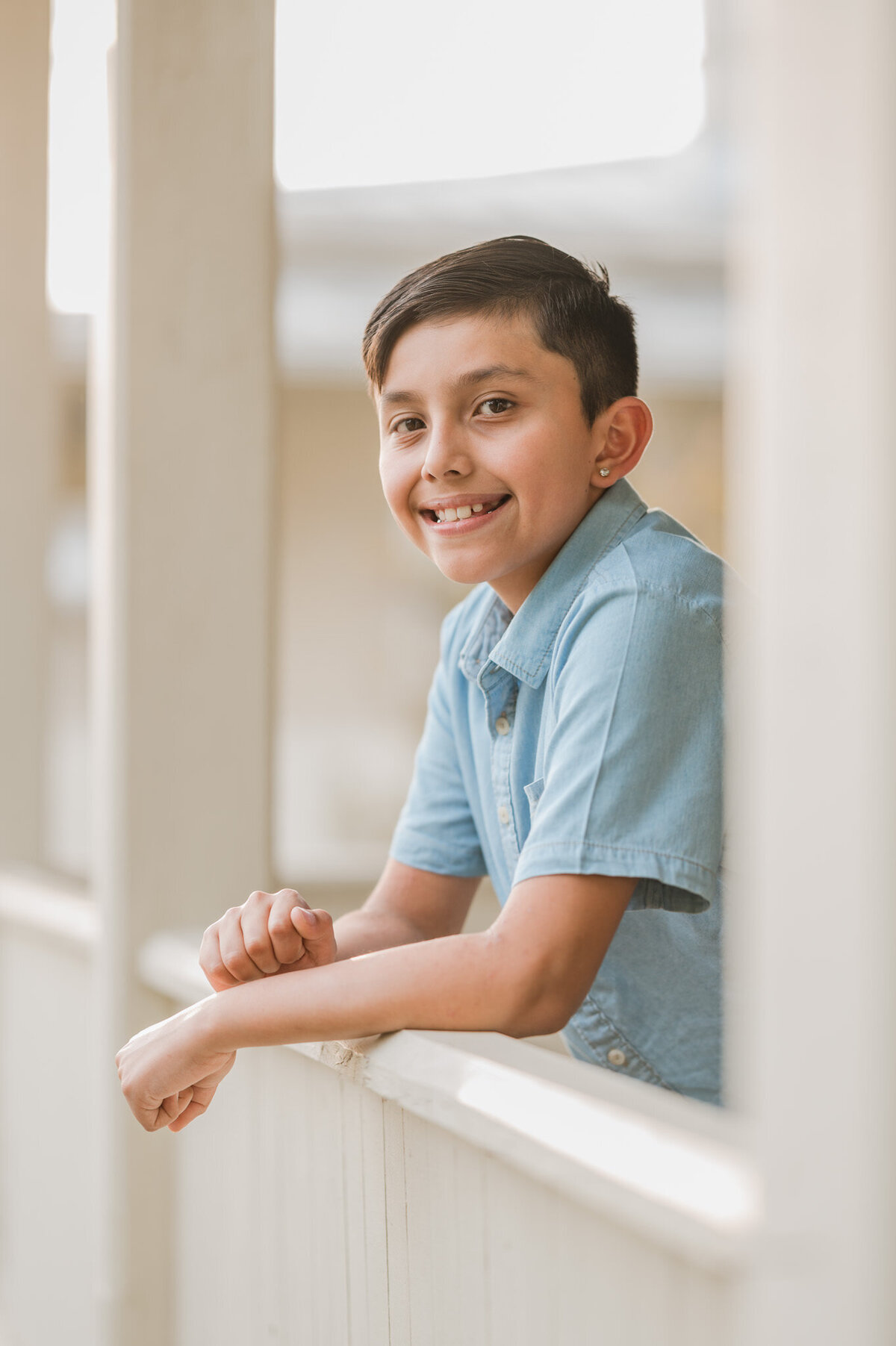 Portrait of a young boy leaning out over a porch railing.