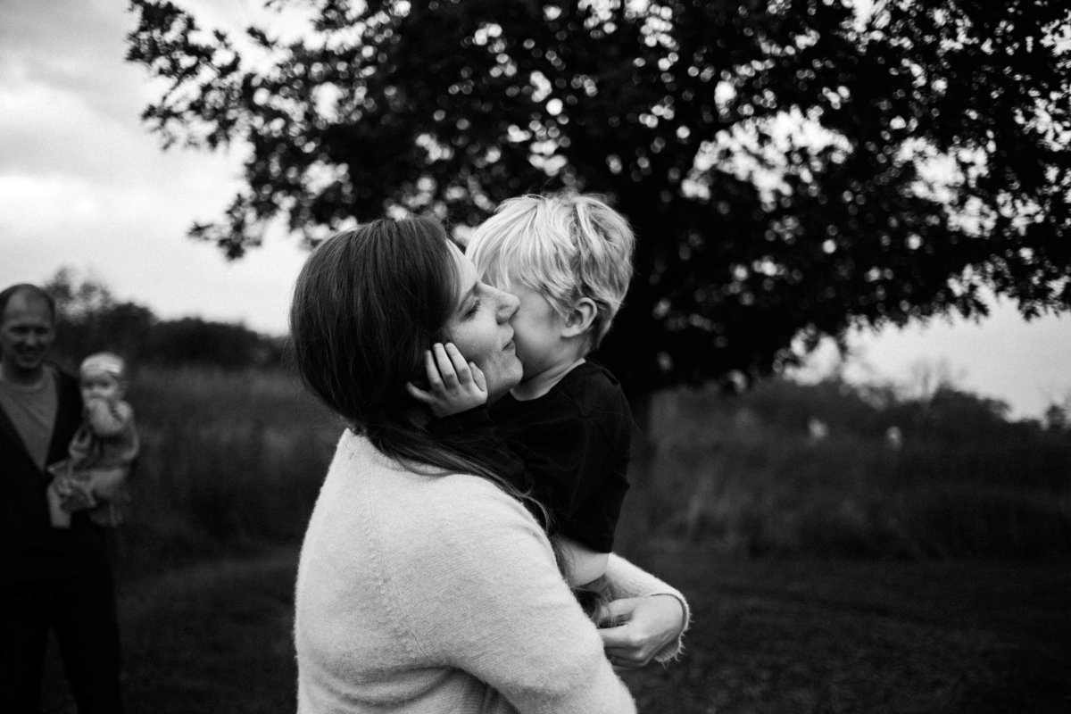 black and white image of a mother hugging and holding her blonde little boy in her arms