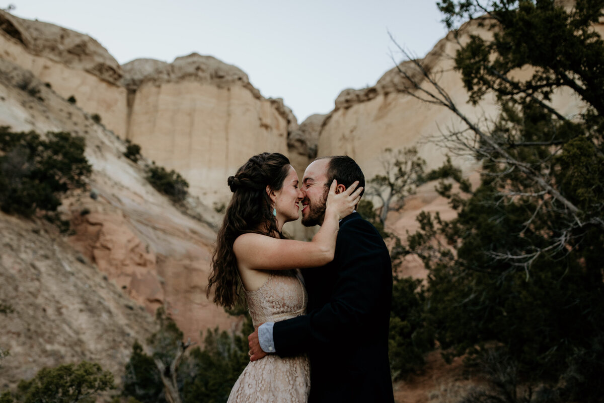 eloping couple kissing in front of a Abiquiu canyon