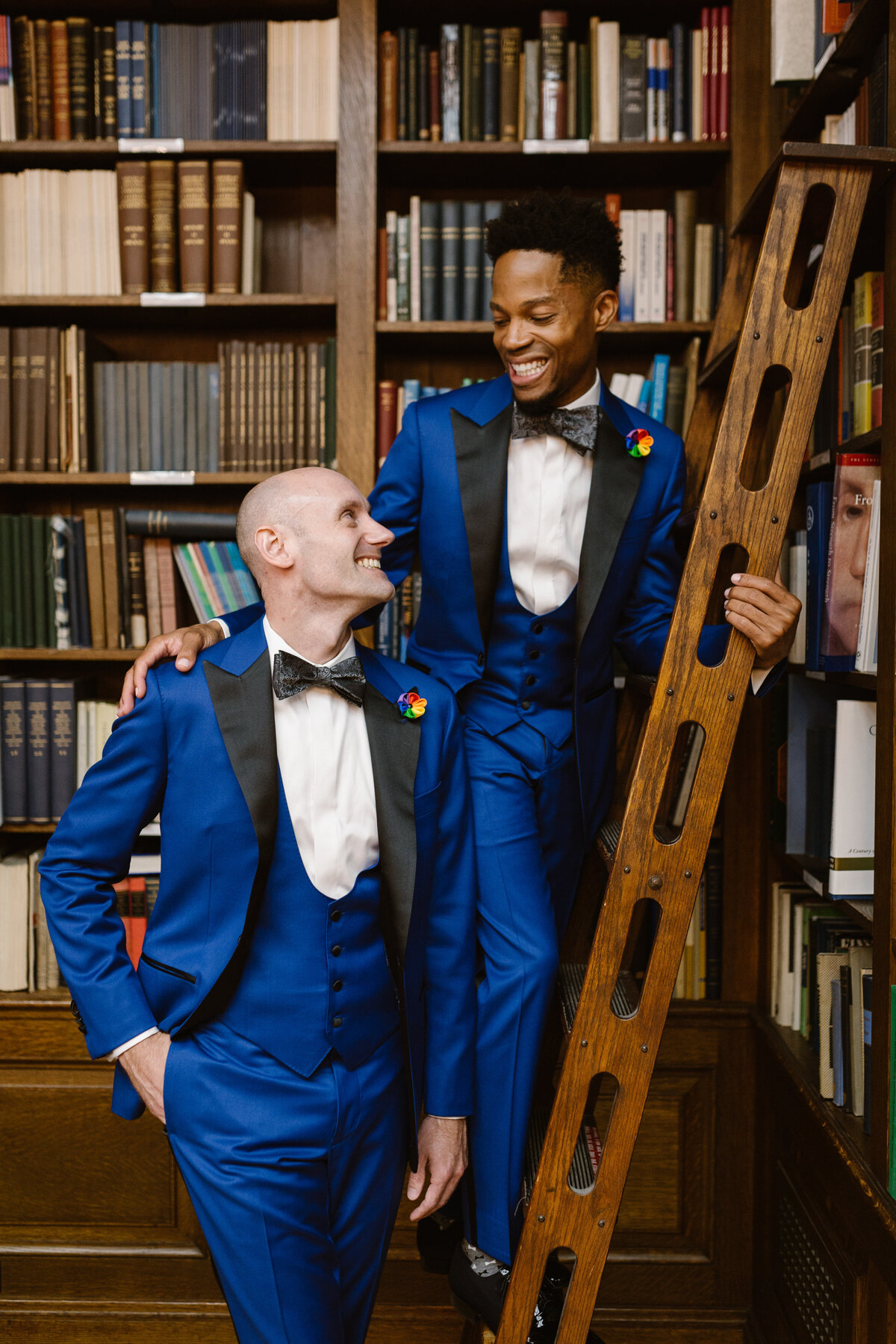 Two grooms standing next to each other while one is on a ladder.